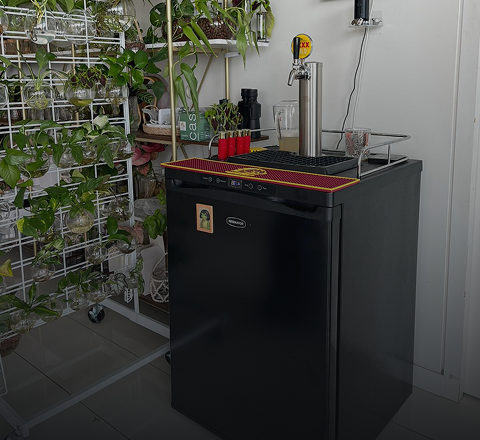 Keg fridge and tap tower built into an outdoor kitchen beside a barbecue